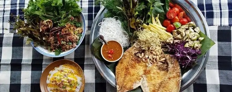 Plates of Thip Khao Laotian food on checkered tablecloth